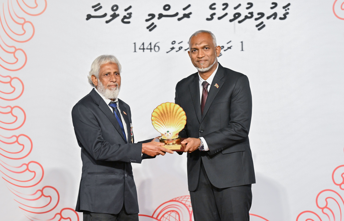 ކުޅިވަރުގެ ދާއިރާ އިން މި އަހަރު ޝަރަފުވެރިކަމުގެ ގައުމީ އިނާމު ހާސިލް ކުރެއްވި އަހުމަދު މުހައްމަދު (ދޮނާ) އާ ރައީސް މުއިއްޒު ހަދާނީ ލިޔުން ހަވާލު ކުރައްވަނީ.---ފޮޓޯ: ރައީސް އޮފީސް