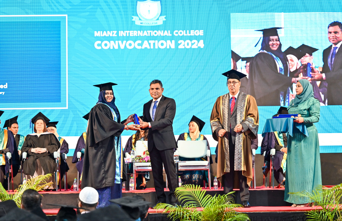 އެމްއައި ކޮލެޖުން މި އަހަރު ގްރެޖުއޭޓްވި ދަރިވަރަކާ ކުރީގެ ނައިބު ރައީސް ފައިސަލް ސެޓްފިކެޓް ހަވާލު ކޮށްދެއްވާއިރު، އަރިހުގައި އެ ކޮލެޖުގެ ޗެއާމަން އަހުމަދު މޮއްޓާކީ.--- ފޮޓޯ: ފަޔާޒު މޫސާ | މިހާރު