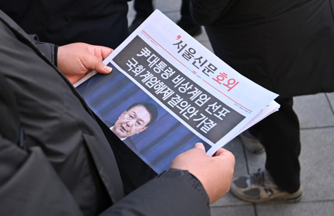 ދެކުނު ކޮރެއާގެ ރައީސް ކުއްލި ހާލަތު އުވާލެއްވި ހަބަރު ނޫހަކުން މީހަކު ކިޔަނީ. --ފޮޓޯ: އޭއެފްޕީ