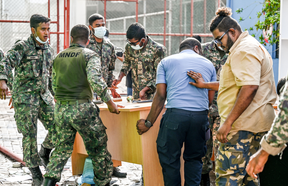 މ. ގްރީން ބިލްޑިންގައި ހިންގާ އޮފީސްތަކުން ސަލާމަތްކުރެވެން ހުރި ބައެއް ސާމާނު ސިފައިންނާއި ފުލުހުން ގުޅިގެން އެތަނުން ނެރެނީ.-- ފޮޓޯ: ނިޝާން އަލީ | މިހާރު