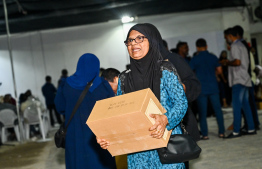 A woman walking away with her fish can case. Distribution will continue until the end of February -- Photo: Nishan Ali | Mihaaru