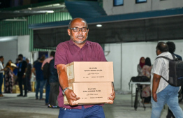 A person walking with their tuna can cases -- Photo: Nishan Ali | Mihaaru