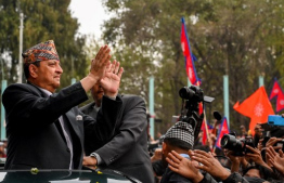 Nepal's former King Gyanendra Bir Bikram Shah Dev waves as he arrives at Tribhuwan International Airport in Kathmandu on March 9, 2025. (Photo by PRAKASH MATHEMA / AFP)