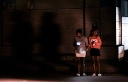 Cubans stand on a corner during a general blackout in Havana on March 14, 2025. Cuba suffered another general blackout on March 14, 2025, caused by a failure in its national electricity system, the Ministry of Energy and Mines reported. (Photo by YAMIL LAGE / AFP)