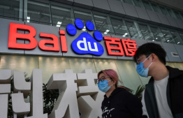 (FILES) People walk past a Baidu logo outside the company headquarters in Beijing on February 2, 2024. Chinese internet search giant Baidu released a new artificial intelligence reasoning model on March 16, 2025 and made its AI chatbot services free as ferocious competition grips the sector. (Photo by Jade GAO / AFP)