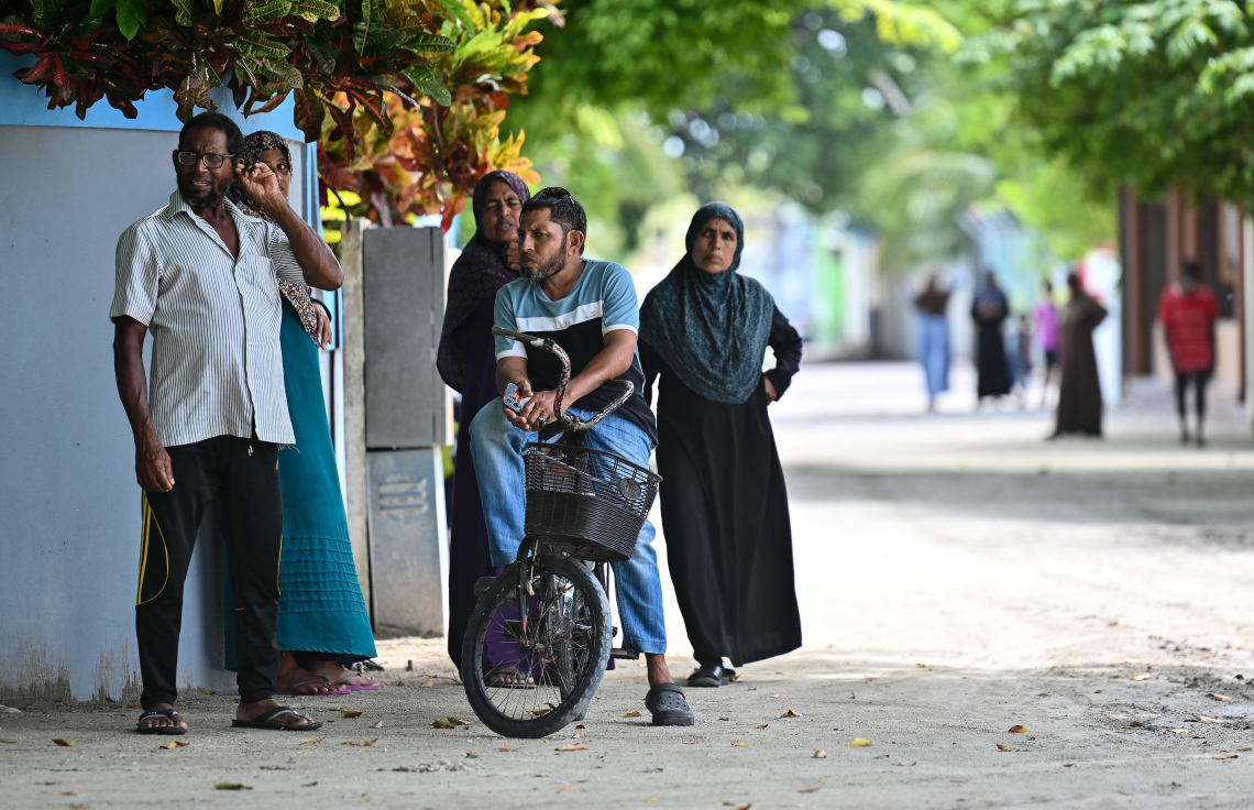 އއ. މާޅޮހުގައި އަބްދުއްރަހަހުމާން އާދަމްގެ ހަށިގަނޑު މި ރަށު ސިއްހީ މަރުކަޒުގައި ބާއްވާފައި އޮތް އިރު، މަރުކަޒު ބޭރުގައި ބައެއް މީހުން ހަރަކާތްތެރިވަނީ--- ފޮޓޯ: ފަޔާޒު މޫސާ | މިހާރު