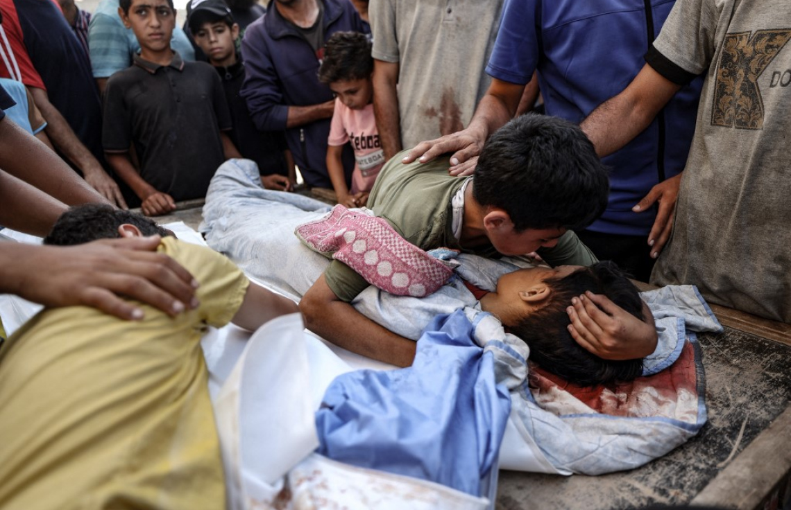 އިޒްރޭލުން ދިން ހަމަލާއެއްގައި ޝަހީދުވި ކުއްޖެއްގެ ގައިގައި އެހެން ކުއްޖަކު ބައްދާލަނީ. -- ފޮޓޯ: އޭއެފްޕީ