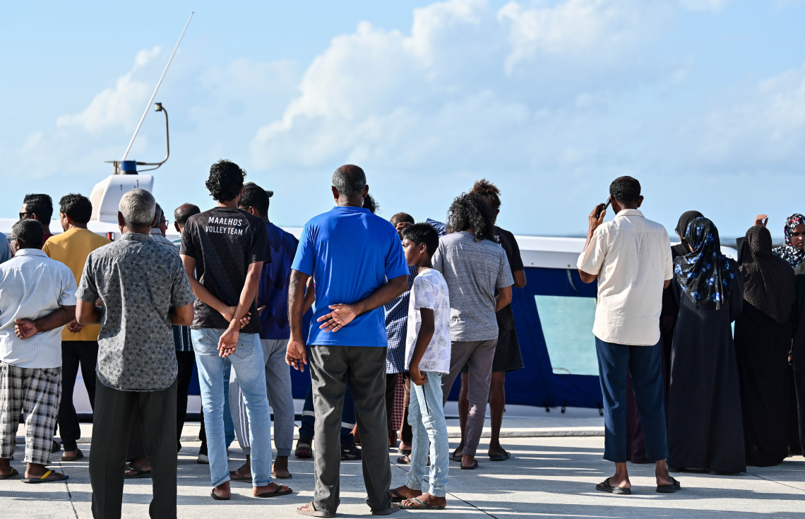 ފުލުހުންގެ އިތުރު ތަހުލީލުތަށް ކުރުމަށް އަބްދުއްރަހުމާންގެ ހަށިގަނޑު މާލެ ފޮނުވައިލުމަށް ފުލުހުންގެ ލޯންޗަށް އެރުވި ވަގުތު އެ ރަށުގެ ބައެއް މީހުން ބަނދަރު ސަރަހައްދަށް އެއްވެފައި.--- ފޮޓޯ: ފަޔާޒު މޫސާ | މިހާރު