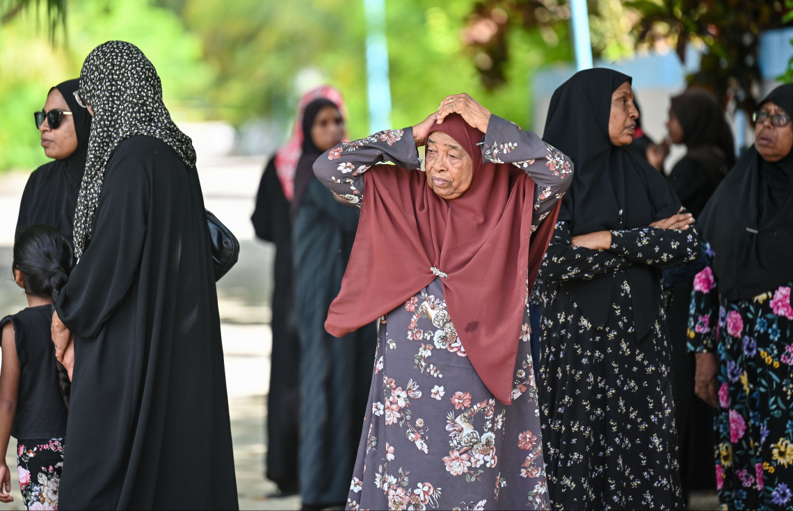 އަބްދުއްރަހުމާންގެ ހަށިގަނޑު މާލެ ފޮނުވައިލުމަށްޓަކައި ފުލުހުންގެ ލޯންޗަށް އެރުވި ވަގުތު އެ ސަރަހައްދުގައި އެ ރަށު އަންހެންވެރިން މަޑުކޮށްލައިގެން: "މިއީ މި ރަށު މީހުން ކުރާ ޒާތުގެ ކަމެއް ނޫން،" ކަމަށް ގިނަ ބަޔަކު ގަބޫލުކުރޭ.---ފޮޓޯ: ފަޔާޒު މޫސާ | މިހާރު