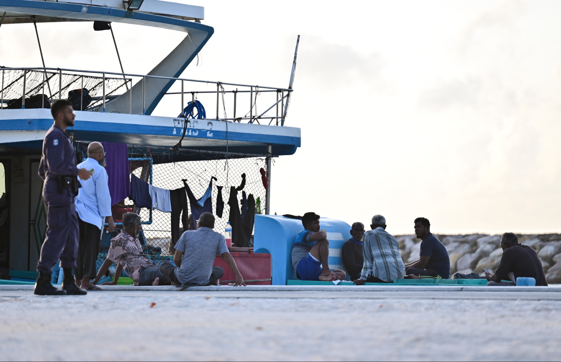 މާޅޮހުގެ ބަނދަރުގައި އަޅާފައިވާ މަސް ދޯންޏެއްގެ ތެރޭގައި އެ ދޯނީގެ ބައެއް ފަޅުވެރިން މަޑުކޮށްލައިގެން ތިބި އިރު ފުލުހަކު ޑިއުޓީގައި: ފުލުހުންގެ ހުއްދައާ ނުލައި މި ރަށަށް އަރައި ފޭބުން ވަނީ މަނާކޮށްފައި.--- ފޮޓޯ: ފަޔާޒު މޫސާ | މިހާރު