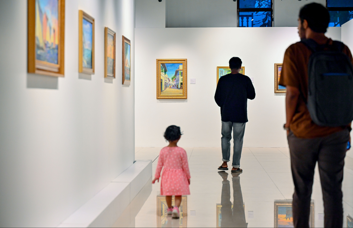 ރާއްޖޭގެ އެހާރާއި މިހާރުގެ ދިރިއުޅުން ދައްކުވައިދޭ ކުރެހުންތަކާ އެކު، އާޓް ގެލެރީގައި މިހާރު ކުރިއަށް ގެންދާ މަނާގޭ އަބްދުﷲ ފާއިޒުގެ ކުރެހުމުގެ މައުރަޒަށް ޒިޔާރަތްކުރި މީހަކު ކުޑަކުއްޖަކު ގޮވައިގެން ކުރެހުންތައް ބަލައިލަނީ: މި މަހުގެ 16 އިގެ ނިޔަލަށް މި މައުރަޒު ކުރިއަށް ގެންދާނެ.---ފޮޓޯ: ނިޝާން އަލީ| މިހާރު