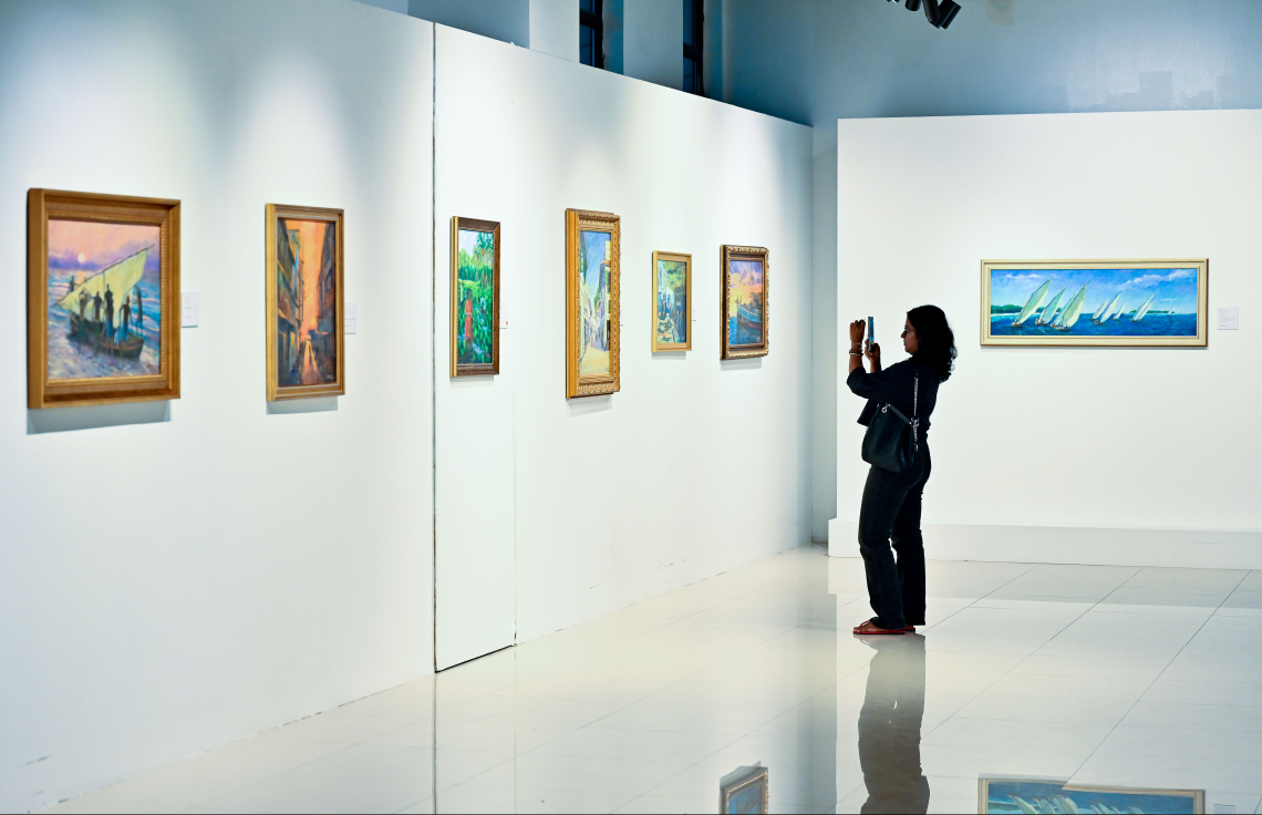 ރާއްޖޭގެ އެހާރާއި މިހާރުގެ ދިރިއުޅުން ދައްކުވައިދޭ ކުރެހުންތަކާ އެކު، އާޓް ގެލެރީގައި މިހާރު ކުރިއަށް ގެންދާ މަނާގޭ އަބްދުﷲ ފާއިޒުގެ ކުރެހުމުގެ މައުރަޒަށް ޒިޔާރަތްކުރި ޒުވާނަކު ކުރެހުމުގެ ފޮޓޯއެއް ނަގަނީ: މި މަހުގެ 16 އިގެ ނިޔަލަށް މި މައުރަޒު ކުރިއަށް ގެންދާނެ.---ފޮޓޯ: ނިޝާން އަލީ| މިހާރު