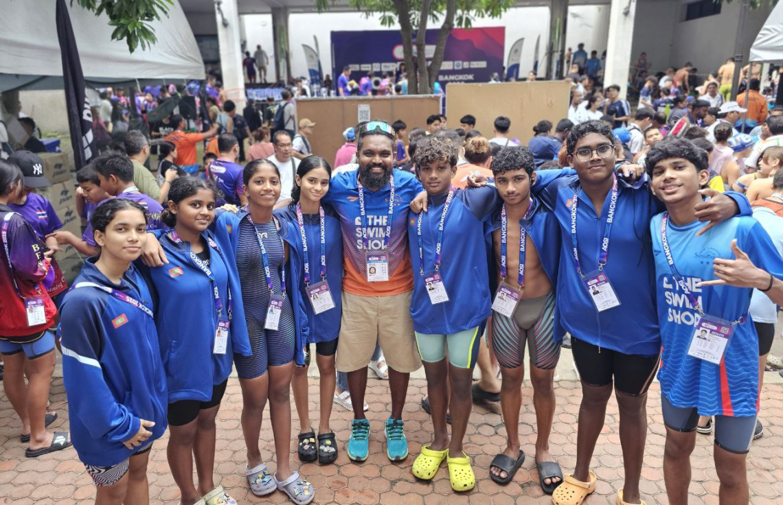 ތައިލެންޑުގެ ބެންކޮކްގައި ބޭއްވި އޭޝިއަން އޯޕަން ސްކޫލް އިންވިޓޭޝަނަލް ޝޯޓްކޯސް މުބާރާތުގައި ރާއްޖޭގެ ނިއު ލެގޫން ޓީމުގެ ފަރާތުން ބައިވެރިވި މިކްސްޑް ރިލޭ ޓީމުގެ ބައިވެރިންނާ އެކު ކޯޗު އަލީމް ފޮޓޯއެއް ނަގަނީ.