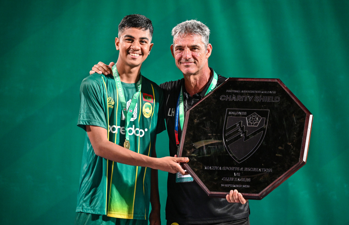 އީގަލްސް ބަލިކޮށް އެފްއޭއެމް ޗެރިޓީ ޝީލްޑް ކާމިޔާބު ކުރުމަށް ފަހު، ޒުވާން ކުޅުންތެރިޔާ މުހައްމަދު އިލާން އިމްރާނާއި މާޒިޔާގެ ކޯޗު ލުއިސްމާ ހެނާންޑޭޒް ޝީލްޑް އެކު، ފޮޓޯއަކަށް ހުއްޓިގެން.--- ފޮޓޯ: ފަޔާޒު މޫސާ | މިހާރު