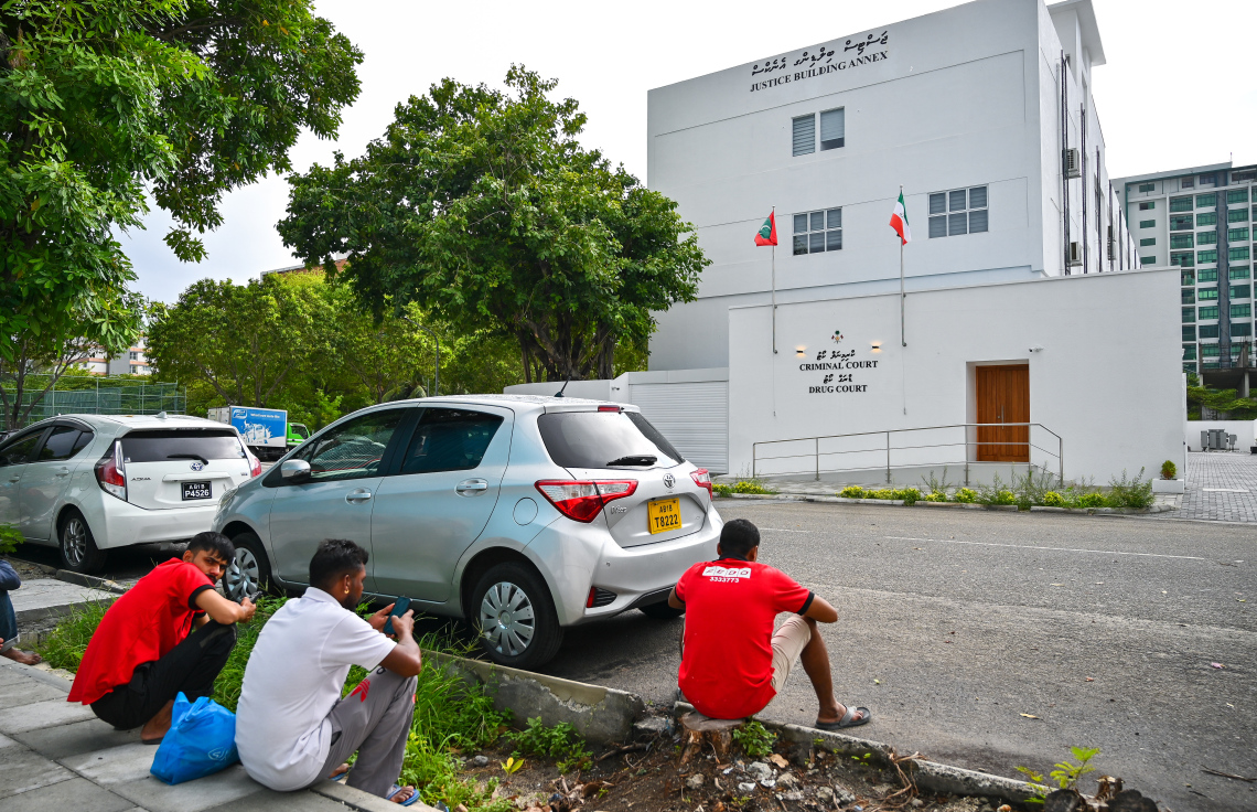 ހުޅުމާލޭގައި ހެދި ކްރިމިނަލް ކޯޓާއި ޑްރަގް ކޯޓު ހިންގާ އިމާރާތް ކައިރީގައި ބަޔަކު އިށީނދެގެން.---ފޮޓޯ: ފަޔާޒު މޫސާ| މިހާރު