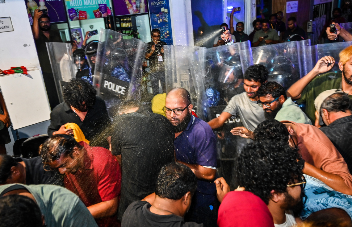 އިދިކޮޅު އެމްޑީޕީގެ ބޮޑު އެއްވުމުގެ ބައިވެރިން ފުލުހުންގެ އެންގުމާ ހިލާފަށް މަޖީދީ މަގުން ދާން މަސައްކަތް ކުރުމުން، އެ މީހުން ފަހަތަށް ޖައްސަން ފުލުހުން ޕެޕާސްޕްރޭ ޖަހަނީ.---ފޮޓޯ: ފަޔާޒު މޫސާ| މިހާރު