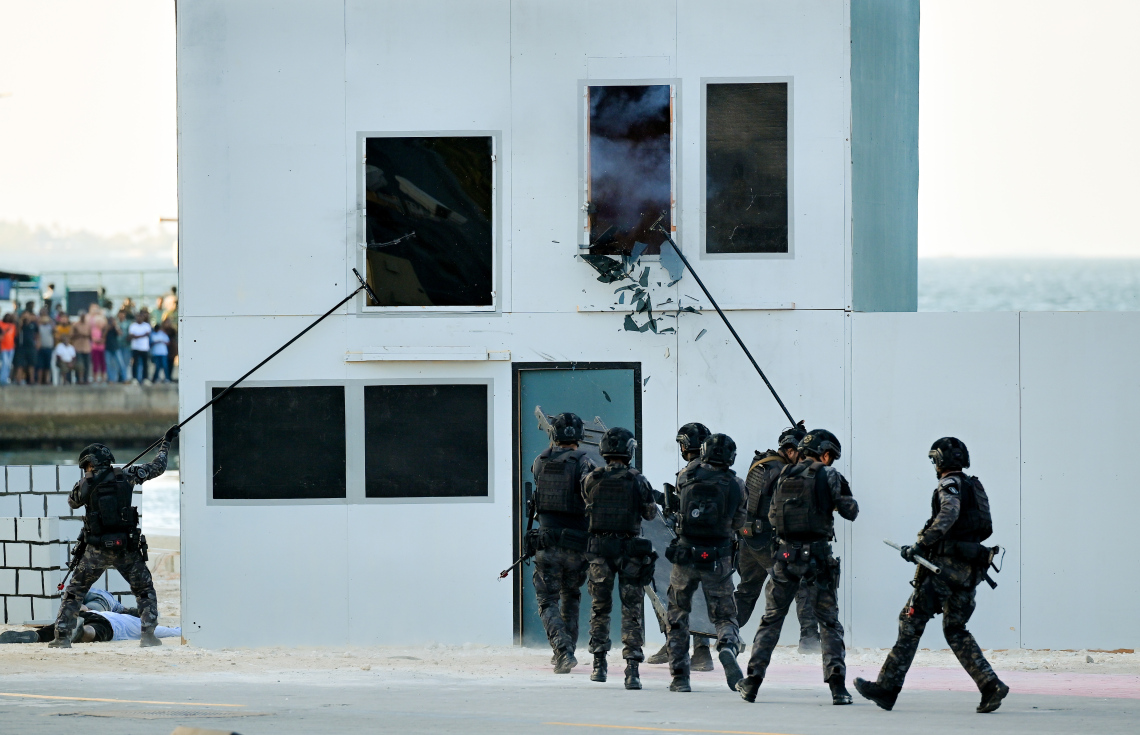 މި އަހަރުގެ ނަސްރުގެ ދުވަހާ ގުޅިގެން ޖުމްހޫރީ މައިދާނުގައި ދިވެހި ސިފައިން ދައްކާލި އަސްކަރީ ހުށަހެޅުމުގެ ތެރެއިން، "ދުޝްމަނުން" ރަހީނުކުރި ބަޔަކު ސަލާމަތްކުރަން މަސައްކަތް ކުރަނީ.--- ފޮޓޯ: ނިޝާން އަލީ | މިހާރު