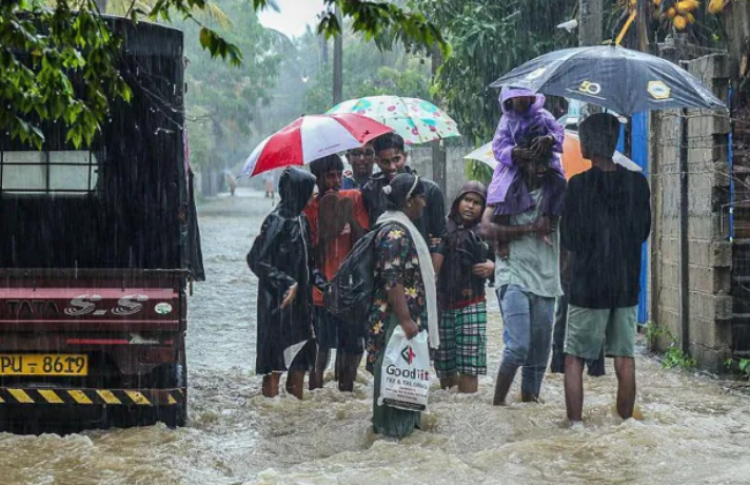 ސްރީލަންކާއަށް އެރި ތޫފާނުގައި ފެންބޮޑުވެފައިވާ ސަަރަހައްދަކުން ރައްކާތެރި ސަރަހައްދަކަށް ދާން ބަޔަކު މަސައްކަތްކުރަނީ. ފޮޓޯ: ގެޓީ އިމޭޖަސް