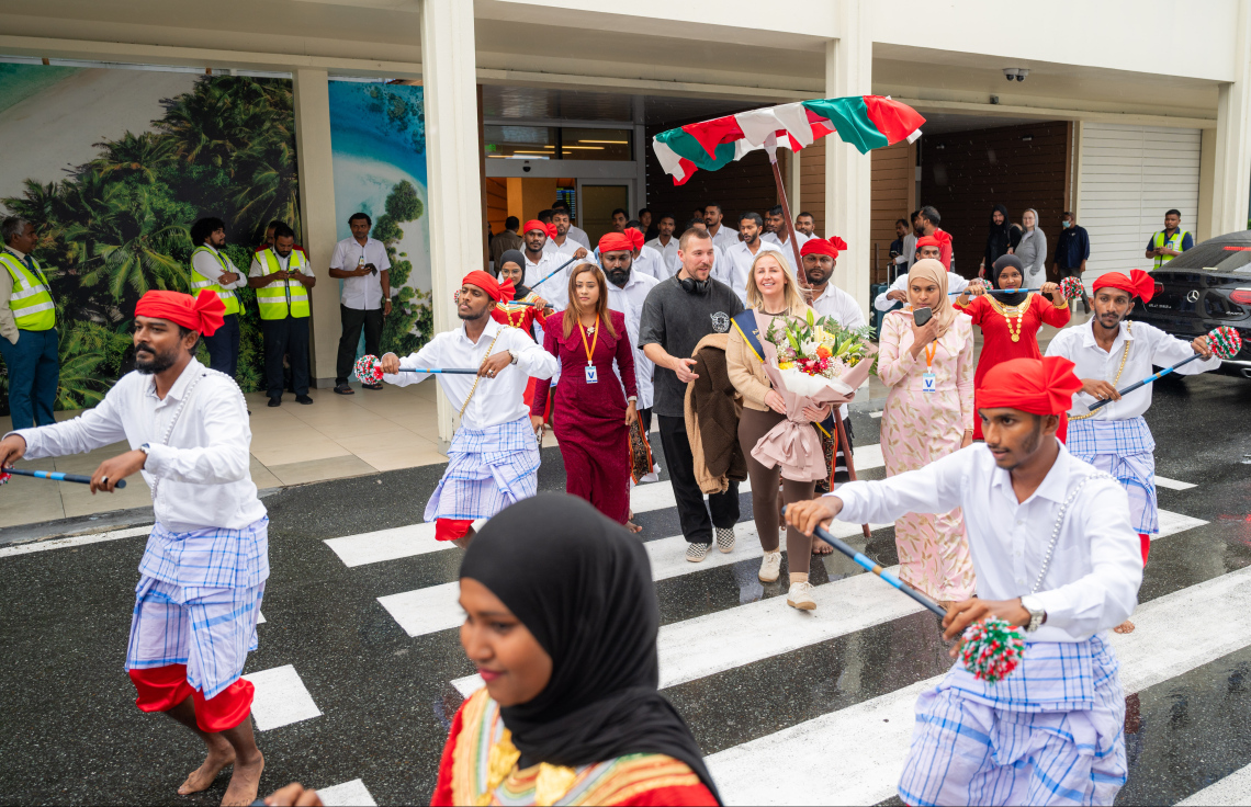 ރާއްޖެ އަށް ޒިޔާރަތްކުރި ދެ މިލިއަން ވަނަ ޓޫރިސްޓުގެ ޝަރަފު ހޯދި އިނގިރޭސި ވިލާތުގެ ބެތަނީ ސާރާ ކާސްވެލް އަށް ދިވެހި ސަގާފީ ހަރަކާތަކުން މަރުހަބާ ކިޔަނީ.---ފޮޓޯ: ނިޝާން އަލީ| މިހާރު