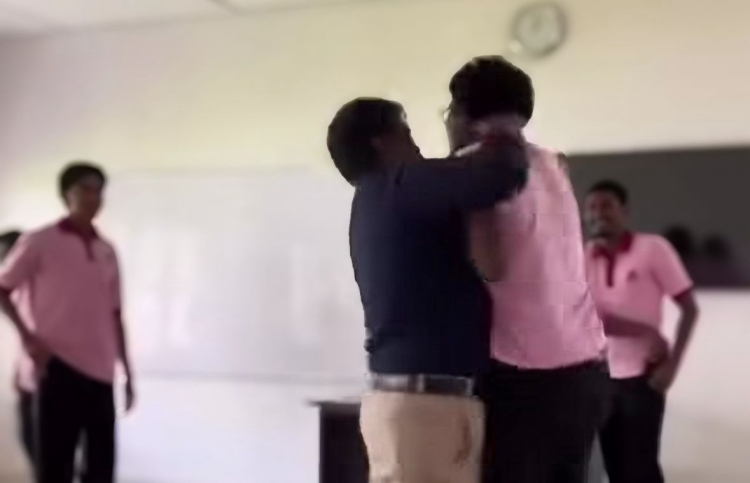 އައްޑޫ ހައި ސްކޫލުގައި ހިންގި މާރާމާރީގައި ޓީޗަރު ދަރިވަރުގެ ކަރުގައި ހިފައިގެން އުޅޭ ވީޑިއޯގެ ސްކްރީންޝޮޓެއް.--