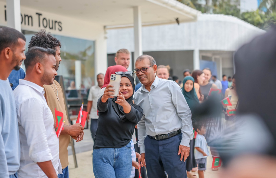 މާފުށީގެ ޓޫރިޒަމް ބްރޭންޑް "ހާޓް އޮފް މޯލްޑިވްސް" އިފްތިތާހުކުރުމަށް ކުރީގެ ރައީސް މުހައްމަދު ނަޝީދު އެ ރަށަށް ވަޑައިގަތުން މަރުހަބާ ކިޔަން ދިޔަ މީހަކާ އެމަނިކުފާނު ސެލްފީއެއް ނަންގަވަނީ.-- ފޮޓޯ: މާފުށި ކައުންސިލް